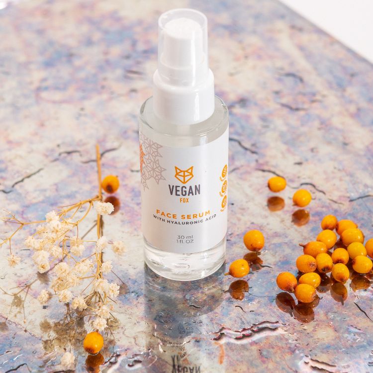 Vegan Fox Hyaluronic Acid Face Serum bottle with pump on a marble surface surrounded by orange berries and white dried flowers