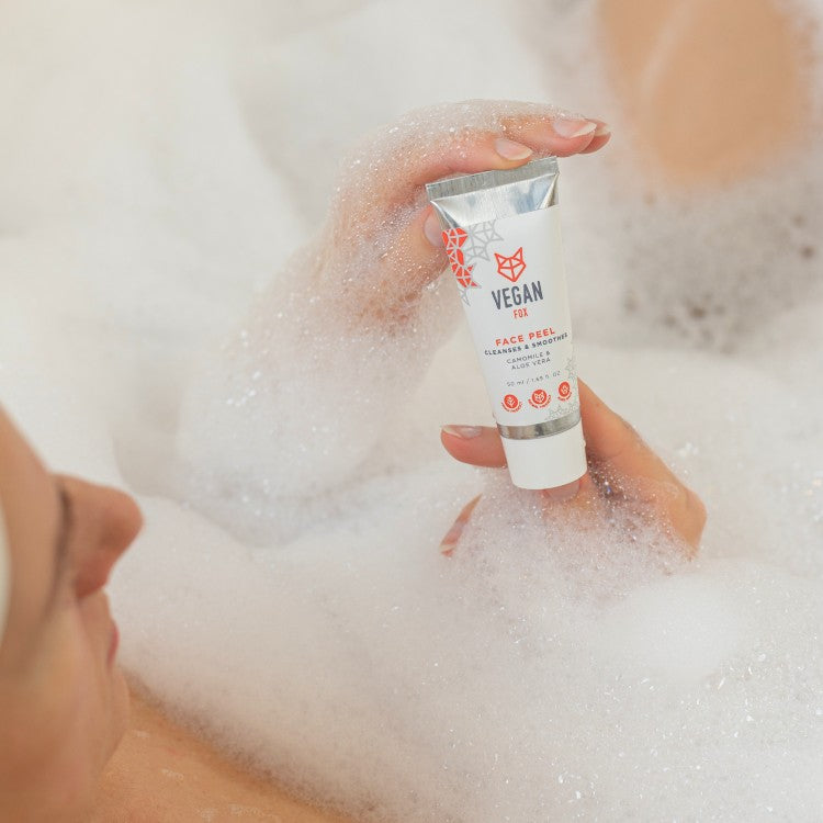 Vegan Fox natural face peel for smoother skin held in hand surrounded by bath foam bubbles